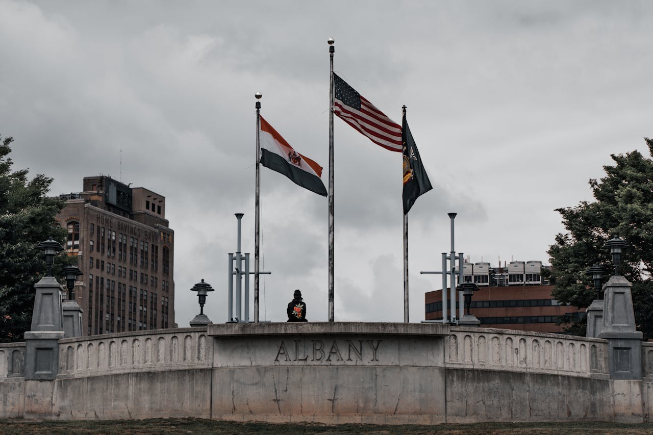 Three flags flying above a stone monument in downtown Albany, New York.