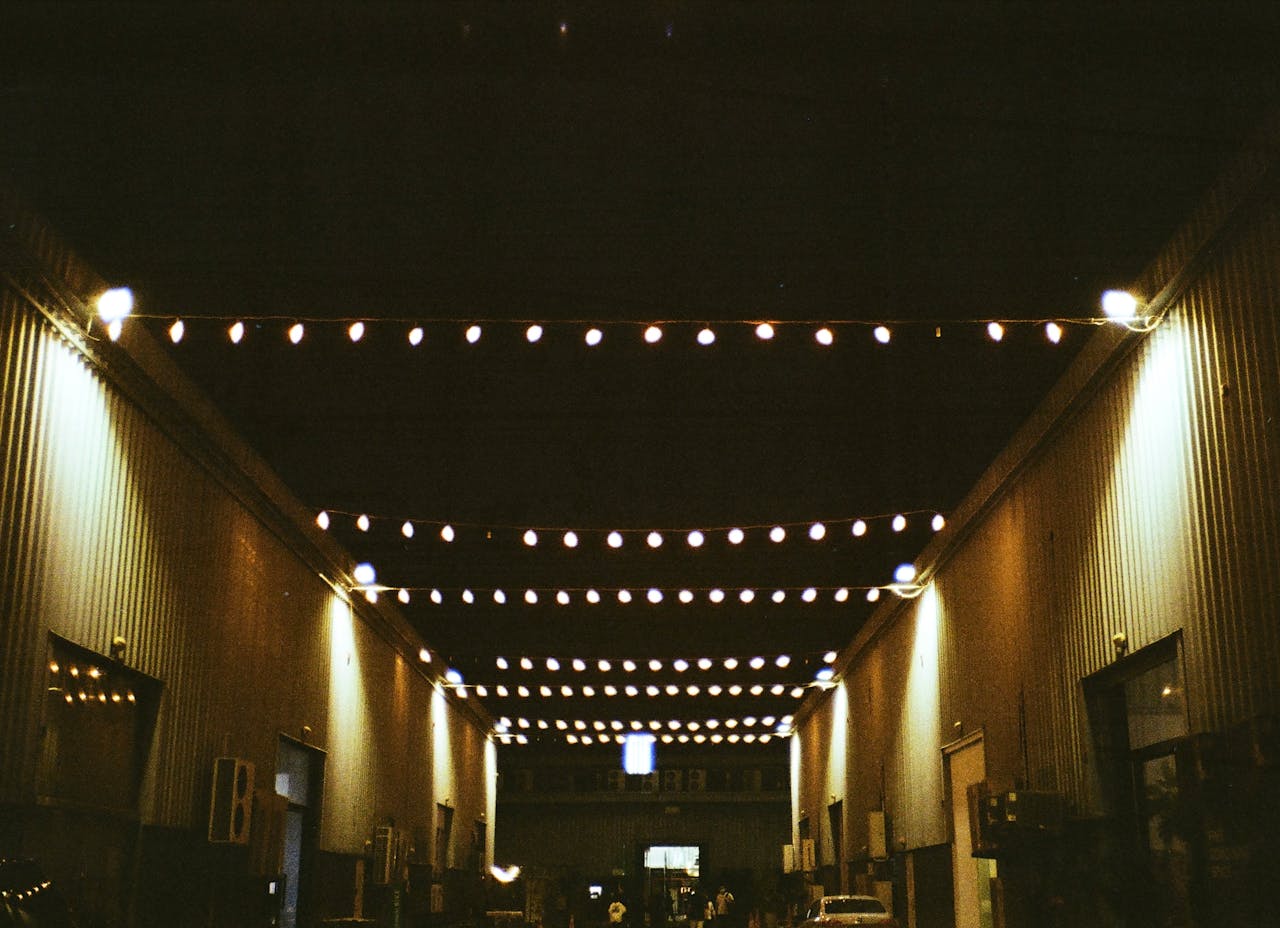 String lights illuminate an industrial walkway at Alserkal Avenue, Dubai, creating a vibrant night scene.